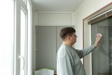 Fototapeta premium Man cleans window on balcony in a residential space during daytime
