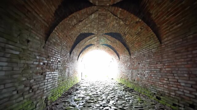 Light at end of old brick tunnel, representing an escape or new beginning journey through a historic path
