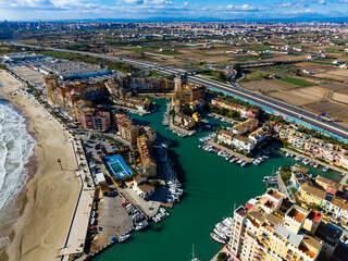 Obraz premium Coastal view of marina area with colorful buildings, water, and fields in background near city during daytime