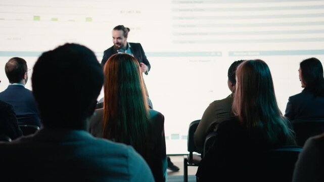 Selective focus of multiethnic audience clapping hands and interacting with presenter, participating at conference for business networking. International summit event in auditorium. Camera A.