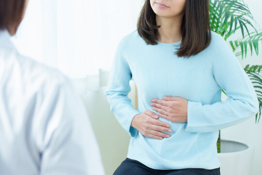 病院で診察を受ける女性　腹痛　体調不良