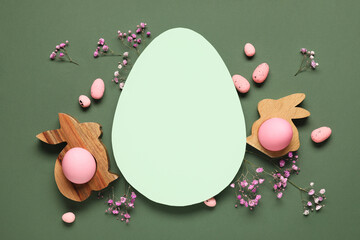 Naklejka premium Composition with egg-shaped blank card, Easter eggs and gypsophila flowers on green background