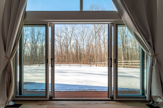 Large sliding glass doors with winter forest view and snow covered landscape