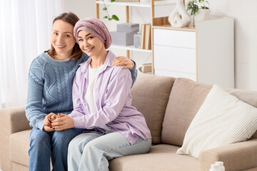 Obraz premium Young woman with her mother after chemotherapy hugging on sofa at home. Brain cancer concept