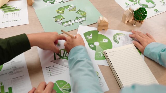 Excellent business people discuss about eco house project on messy table with green energy graph usage choose or analyze alternative power, decrease carbon to save earth. Focus on hand. Delineation.