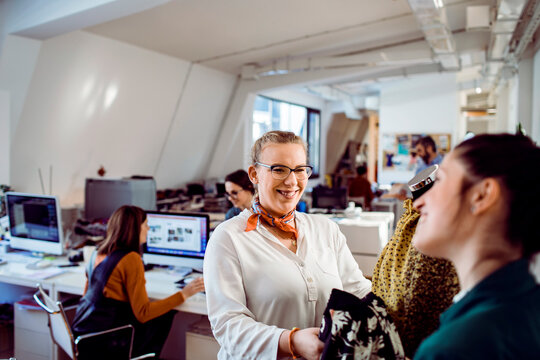 Smiling fashion designer discussing fabrics in modern open office