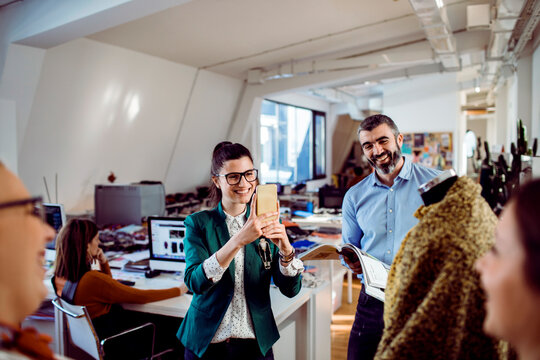 Coworkers photographing garment prototype in fashion design studio