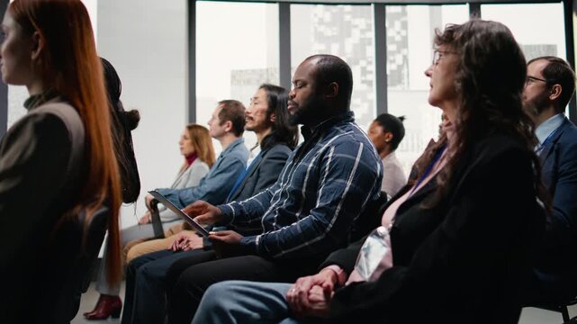 Black male attend professional business event in conference hall with panel presentation. Speaker leads discussion with audience, promoting leadership and entrepreneurship among attendees. Camera A.
