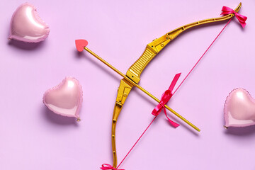 Naklejka premium Golden cupid's arrow and heart shaped balloons on lilac background. Valentine's Day celebration