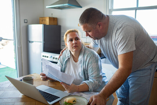 Concerned couple reviewing bills at kitchen table