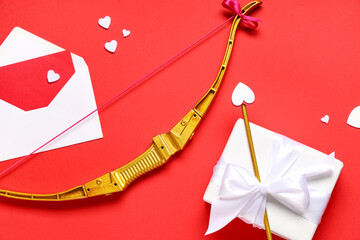 Obraz premium Beautiful composition with cupid's bow, gift box and envelope on red background. Valentine's Day celebration