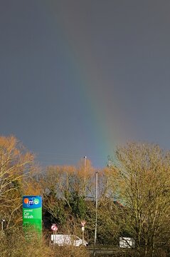 Old branded IMO car wash sign post through trees and rainbow sky. BOSTON Lincs, UK. Feb 06, 2022