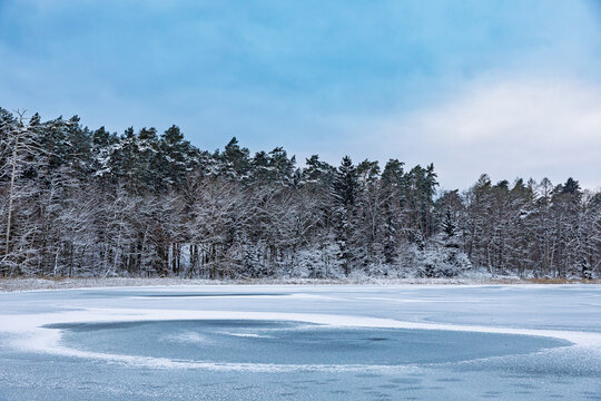 Zugefrorener Bergsee mit Eisring und verschneitem Wald &ndash; klare Winterlandschaft in der Mecklenburgischen Seenplatte, Mecklenburg-Vorpommern