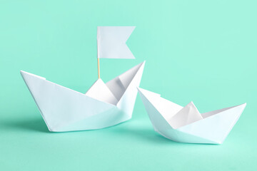 Naklejka premium White paper boats with flag on turquoise background