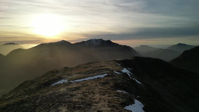 Glen Coe, Scottish Highlands - aerial pan left - view over the mountains in winter with Bidean nam Bian at sun set