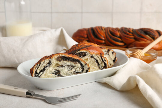 Plate with pieces of sweet poppy seed roll on white table