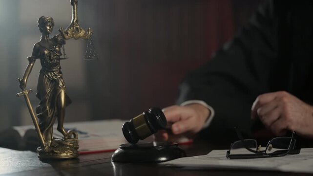 Judge strikes wooden gavel on desk while Statue of Justice stands in the background. courtroom authority, legal decisions, and the rule of law
