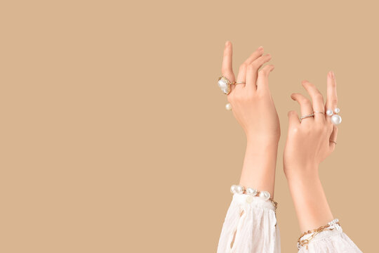 Female hands in beautiful bracelets and rings on brown background