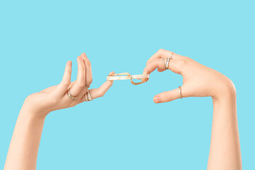 Female hands in golden rings with beautiful bracelet on blue background
