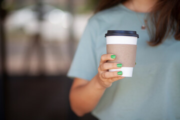 Woman Holding Takeaway Coffee Cup. Young Woman with Takeaway Coffee in Hand. Urban Lifestyle Woman Carrying Coffee Cup. Morning Coffee To Go in Woman's Hand.