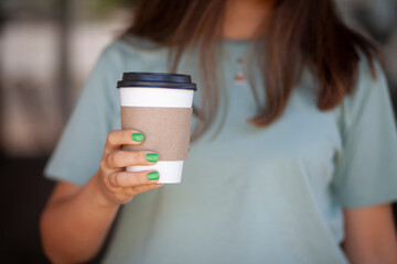 Woman Holding Takeaway Coffee Cup. Young Woman with Takeaway Coffee in Hand. Urban Lifestyle Woman Carrying Coffee Cup. Morning Coffee To Go in Woman's Hand.