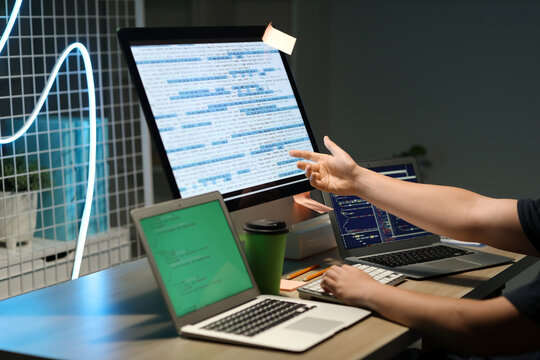 Male programmer pointing at modern computer in office, closeup