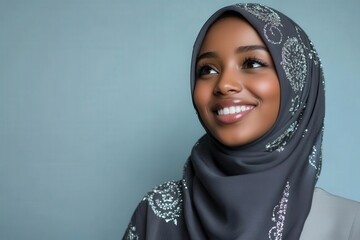 Attractive young woman with dark skin wears a beautifully embellished headscarf while looking upward with a cheerful expression