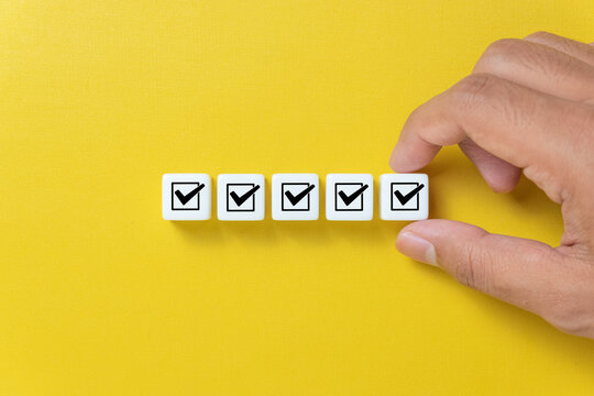 Male hand putting dice with check mark on yellow background. Checklist concept.