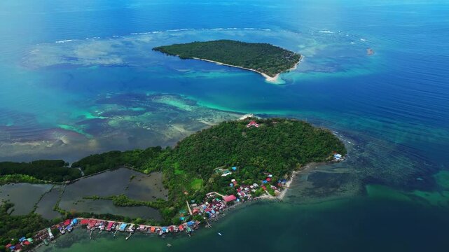 Wide panoramic aerial showing Magalawa Island surrounded by endless turquoise waters and vibrant greenery.