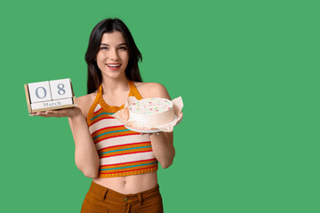 Beautiful young woman with sweet bento cake and cube calendar with date 8 MARCH on green...