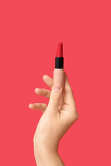 Hand holding lipstick on red background