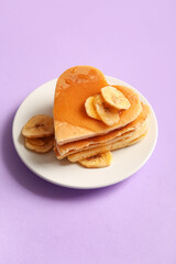Fototapeta premium Plate with tasty pancakes in shape of heart, dried banana and honey on purple background. Valentine's Day celebration