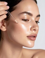 Young Woman Applying Facial Serum for Radiant Skin.
