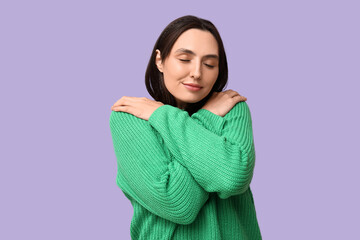 Fototapeta premium Young woman hugging herself on lilac background