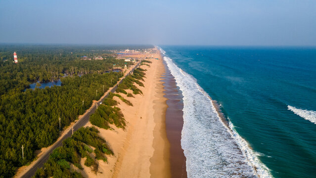 Aerial drone view of Puri Konark Marine Drive coastline in Odisha, India, showing long sandy beach, blue ocean waves, tropical greenery, and scenic coastal landscape