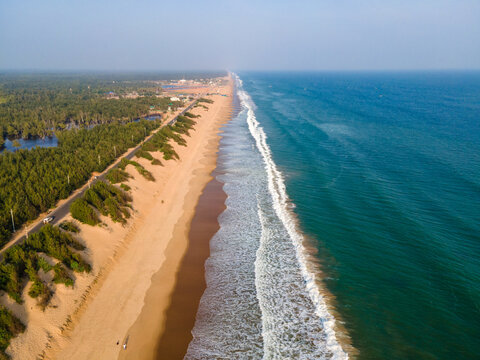 Aerial drone view of Puri Konark Marine Drive coastline in Odisha, India, showing long sandy beach, blue ocean waves, tropical greenery, and scenic coastal landscape