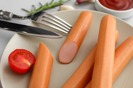 Plate of tasty sausages with tomatoes on grey background
