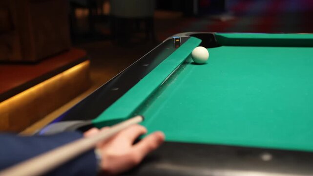 Close-up of a billiards cue shot on a green pool table as the yellow ball drops into the corner pocket, with cue ball near the rail, filmed indoors with shallow depth of field.