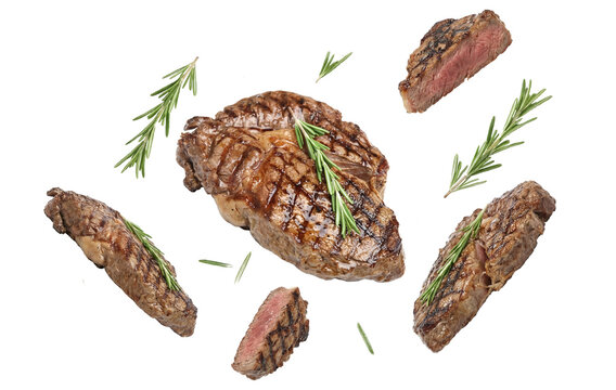 artfully arranged grilled ribeye steak, seasoned with fresh rosemary sprigs, displayed with sliced cuts around it against a stark transparent background.