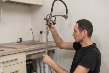 A plumber is replacing a faucet in the kitchen.
