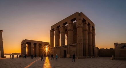 Fototapeta premium Ancient Egyptian temple at sunset with tourists walking around