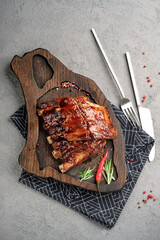 Sticky BBQ pork ribs glazed with sweet and spicy sauce on wooden serving board. Tender grilled spare ribs with rosemary and chili pepper garnish, delicious comfort food meal, top view