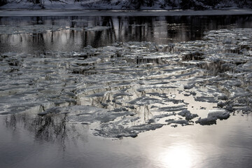 Shimmering ice chunks meander along a partially thawed river, signaling early spring's gentle awakening. Winter's grip loosening © PhotoChur