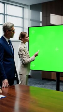 Green Screen tv mockup ready for presentation placed in front of desk while business people working broadroom employees using digital chroma key interactive whiteboard with mock up display monitor