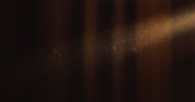Abstract motion blur with warm orange and brown vertical streaks on dark background creating atmospheric artistic effect for modern creative design projects