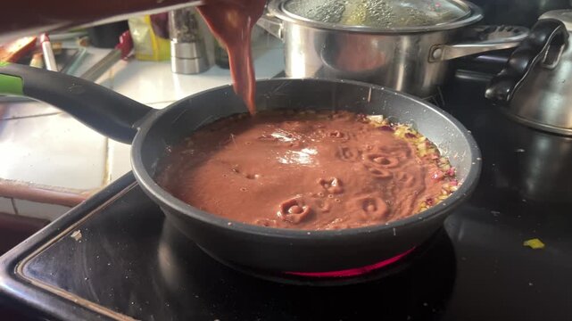 Honduras refried beans cooking in a pan, showing traditional frijoles prepared at home, a common local dish made on the stove using simple ingredients and everyday cooking methods.