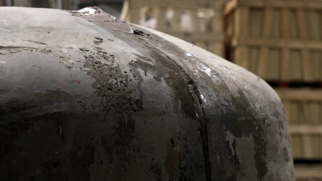 Static close-up shot of a worker&rsquo;s hand applying wet grout along the seam of a curved pizza oven, highlighting texture and craftsmanship during construction.