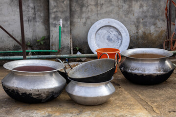 Fototapeta premium Used heavy-duty aluminum cooking pots and iron Karahi on a rooftop surface in Bangladesh. Large-scale culinary preparation vessels from a social gathering or wedding event awaiting washing and care