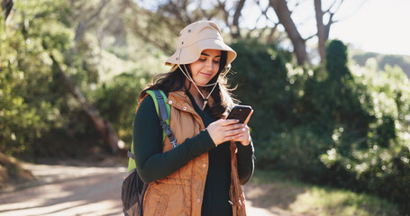 Obraz premium Hiking, chat or woman in nature with phone, message alert or location share in summer hobby. Trekking, typing or female person on path with tech, notification check or journey update on social media.