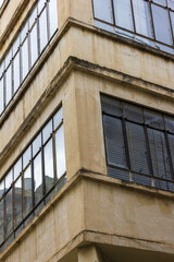 Obraz premium Urban Corner Building With Glass Windows And Weathered Concrete Facade, Architectural Detail